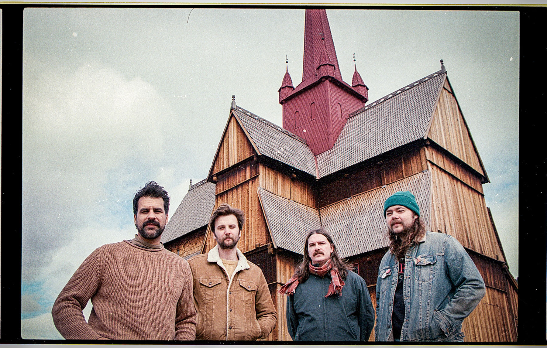The Pink Stones press photo artists stand in front of a model of an Alpine chalet